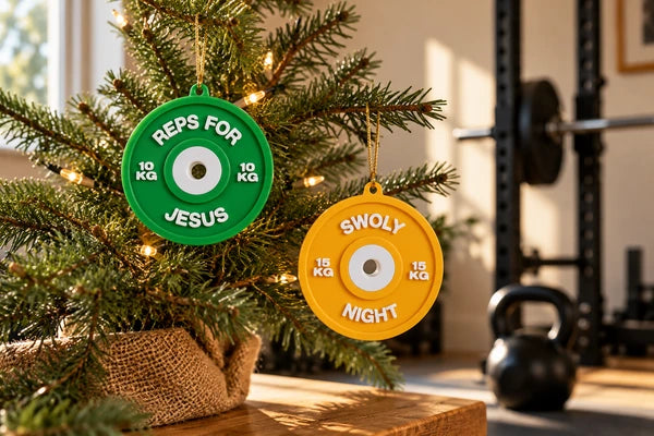Groene Reps for Jesus- en gele Swoly Night-hanger in een kleine kerstboom, met een squatrek en kettlebell op de achtergrond.